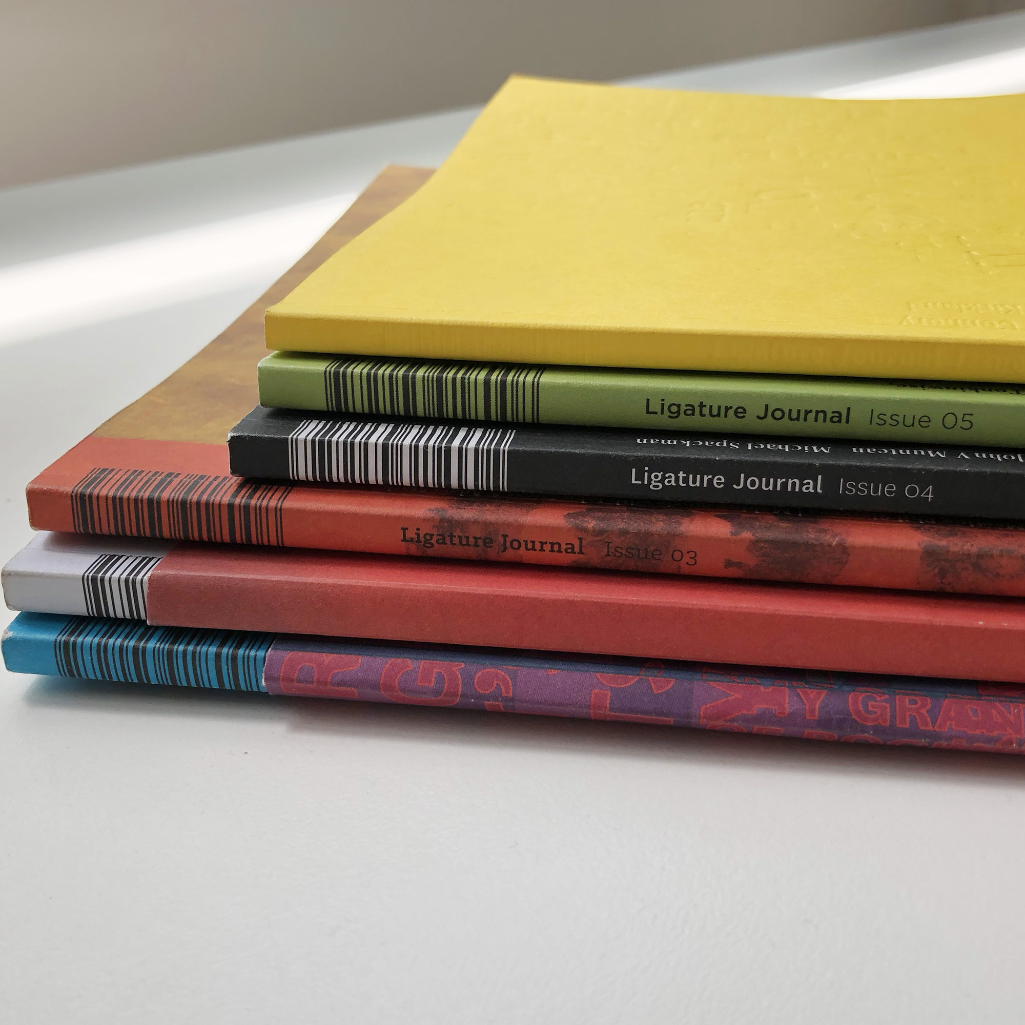 stack of Ligature journal Issues showing part of the magazine spine